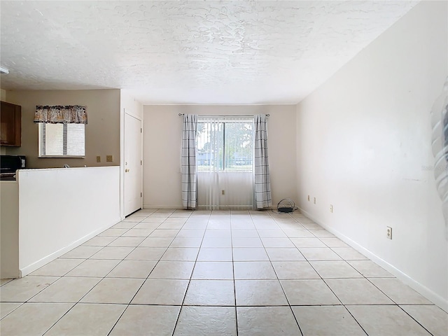 tiled empty room featuring a textured ceiling