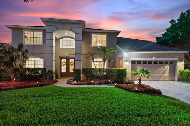 view of front of house featuring french doors, a garage, and a lawn