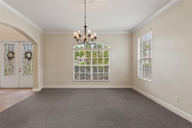 carpeted spare room featuring a notable chandelier, crown molding, and french doors