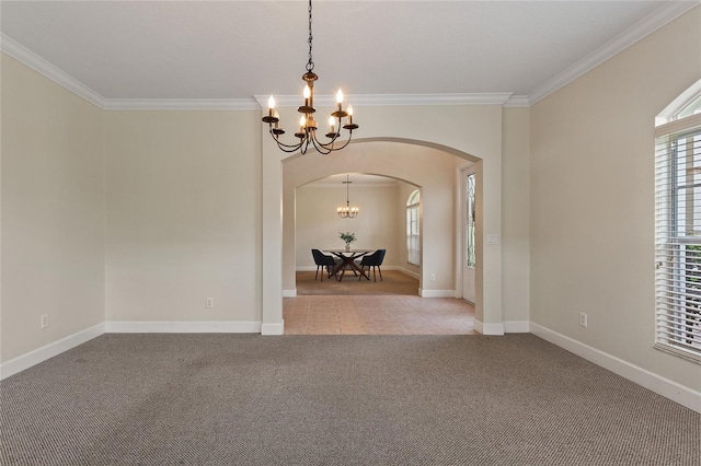 carpeted spare room featuring crown molding and an inviting chandelier