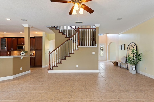 tiled living room with ornamental molding and ceiling fan