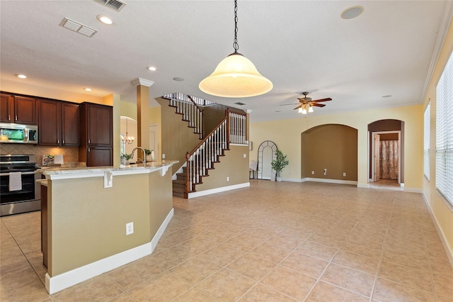 kitchen featuring appliances with stainless steel finishes, hanging light fixtures, a kitchen breakfast bar, light stone countertops, and decorative backsplash