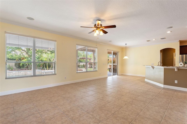 empty room featuring sink, light tile patterned floors, ceiling fan, crown molding, and a textured ceiling