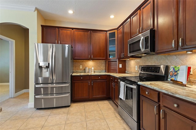 kitchen with light stone counters, stainless steel appliances, tasteful backsplash, and light tile patterned floors