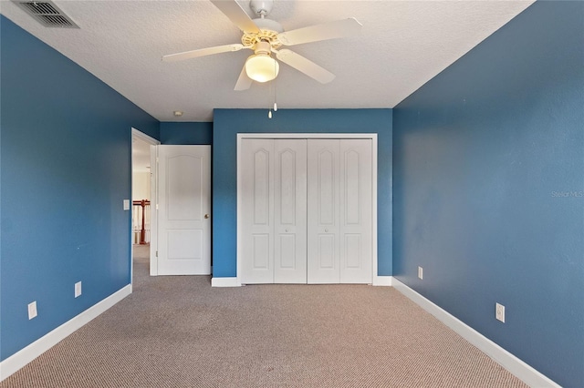 unfurnished bedroom featuring ceiling fan, a closet, a textured ceiling, and carpet flooring