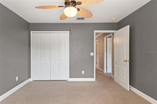 unfurnished bedroom featuring light carpet, a textured ceiling, ceiling fan, and a closet