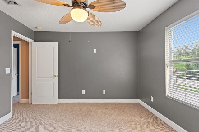 carpeted spare room featuring a textured ceiling and ceiling fan