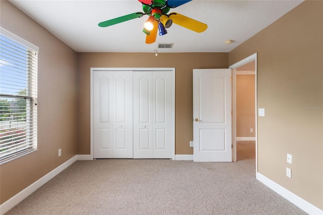 unfurnished bedroom with ceiling fan, light colored carpet, and a closet