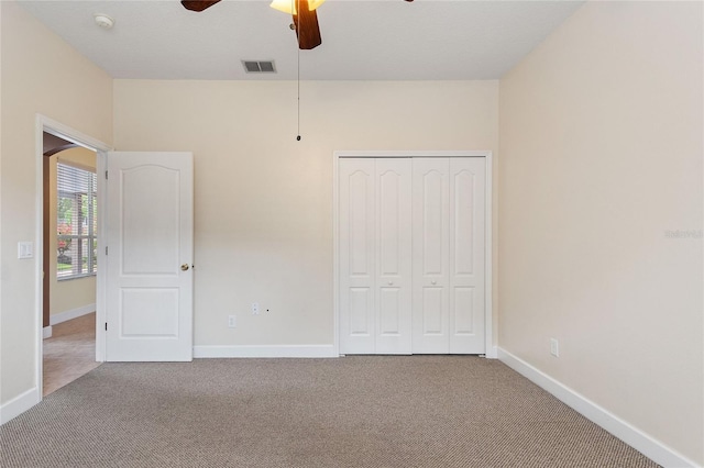 unfurnished bedroom with light carpet, a closet, and ceiling fan