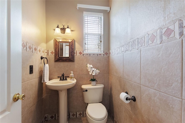 bathroom with sink, tile walls, and toilet