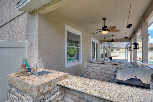 view of patio with ceiling fan, area for grilling, and an outdoor wet bar