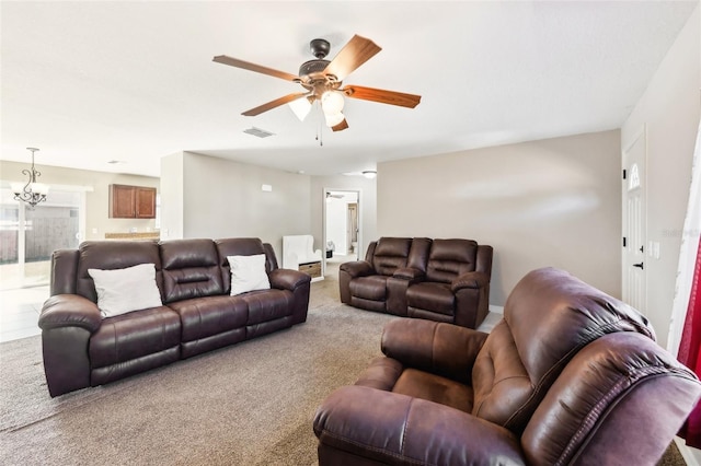 carpeted living room featuring ceiling fan with notable chandelier