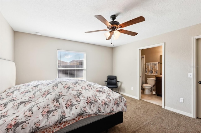 carpeted bedroom featuring ceiling fan, ensuite bath, and a textured ceiling