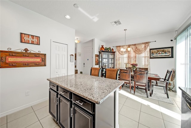 kitchen featuring pendant lighting, a center island, light tile patterned floors, a notable chandelier, and light stone countertops