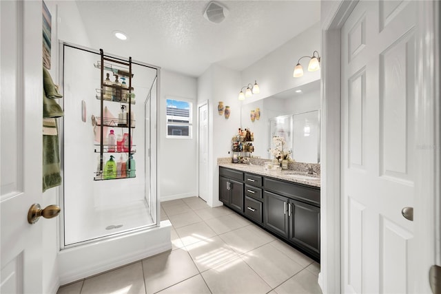 bathroom featuring tile patterned flooring, vanity, a textured ceiling, and walk in shower