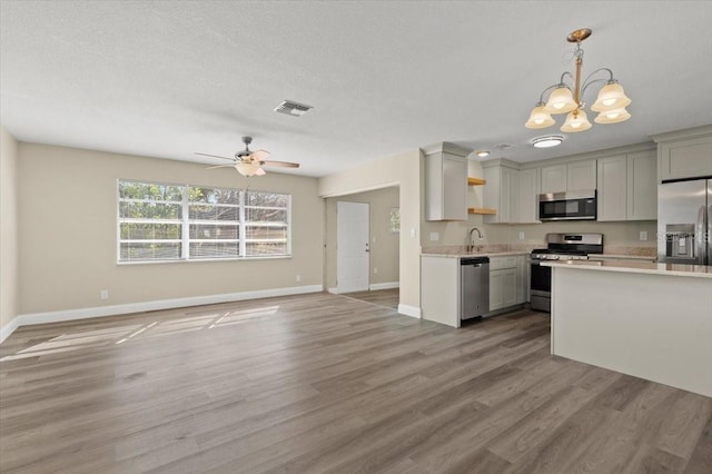 kitchen featuring sink, light hardwood / wood-style flooring, ceiling fan with notable chandelier, stainless steel appliances, and decorative light fixtures