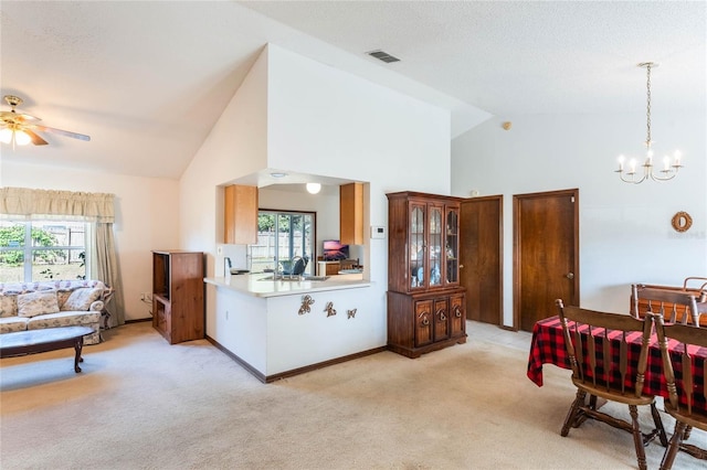 kitchen with light carpet, hanging light fixtures, kitchen peninsula, and a healthy amount of sunlight