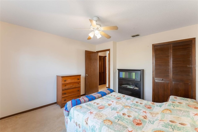 bedroom with light carpet, ceiling fan, and a closet