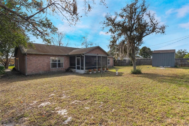 rear view of house with a storage shed, a lawn, and a sunroom