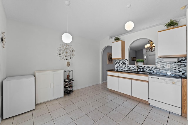 kitchen featuring sink, hanging light fixtures, fridge, white dishwasher, and decorative backsplash