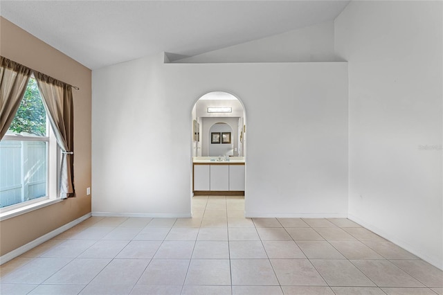 spare room featuring light tile patterned flooring and vaulted ceiling