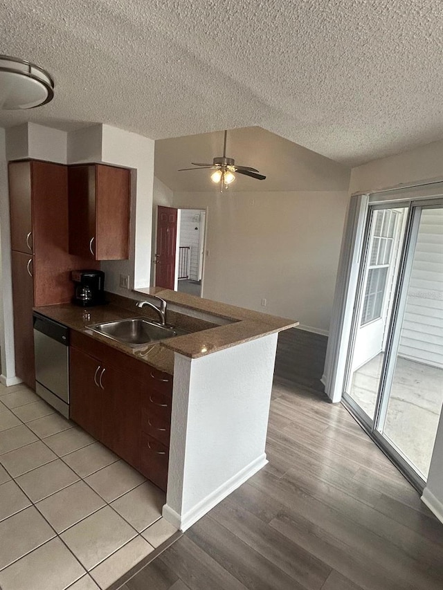 kitchen featuring sink, vaulted ceiling, stainless steel dishwasher, kitchen peninsula, and ceiling fan