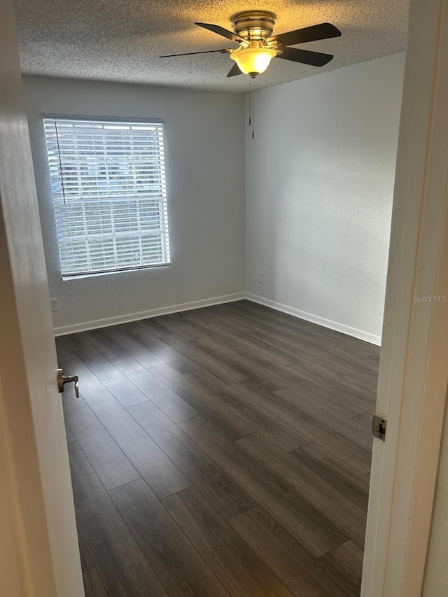 empty room with ceiling fan, dark hardwood / wood-style floors, and a textured ceiling