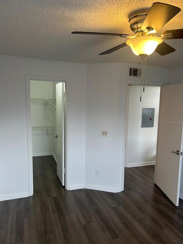 spare room with ceiling fan, dark wood-type flooring, electric panel, and a textured ceiling