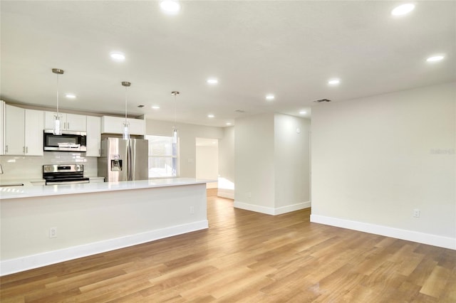 kitchen featuring light hardwood / wood-style flooring, white cabinetry, stainless steel appliances, decorative backsplash, and decorative light fixtures