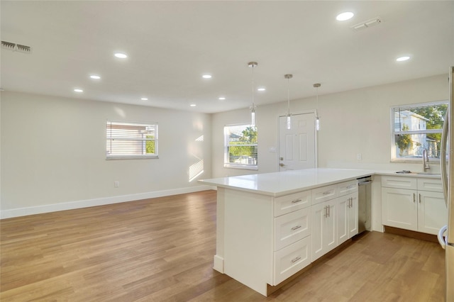 kitchen featuring pendant lighting, kitchen peninsula, light hardwood / wood-style flooring, and white cabinets