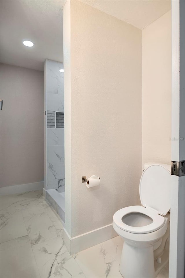 bathroom featuring a tile shower and toilet