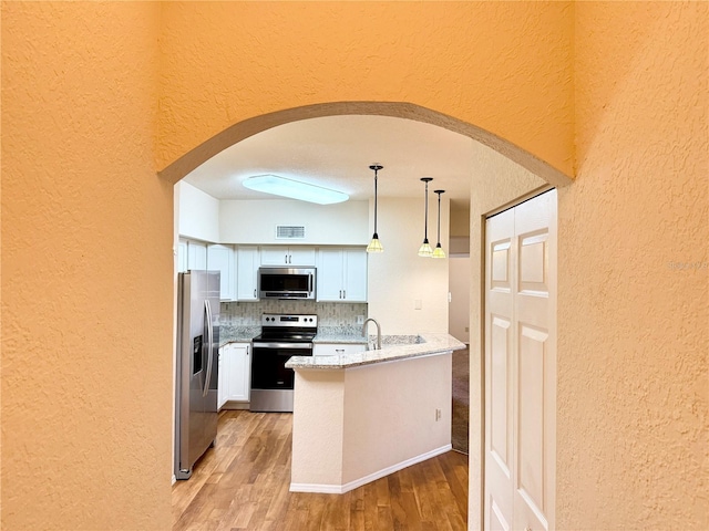 kitchen with pendant lighting, light hardwood / wood-style flooring, white cabinetry, backsplash, and stainless steel appliances