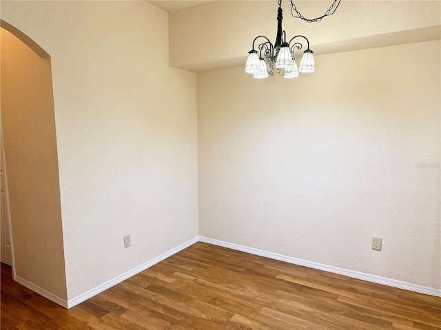 empty room featuring an inviting chandelier and hardwood / wood-style floors