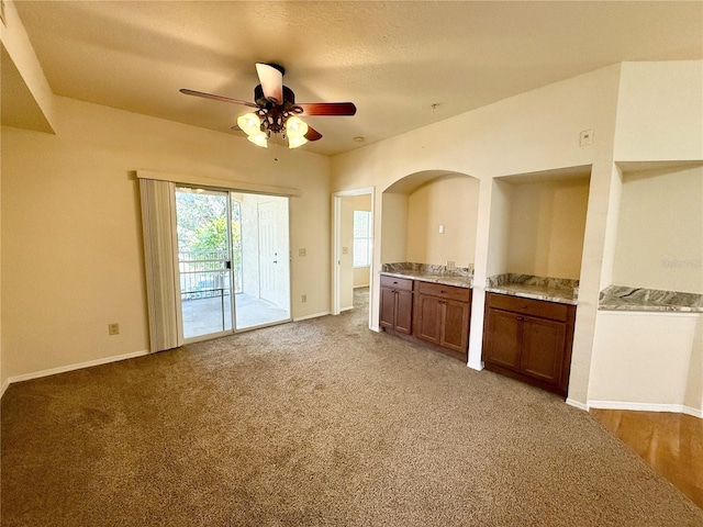 unfurnished living room featuring ceiling fan and carpet flooring