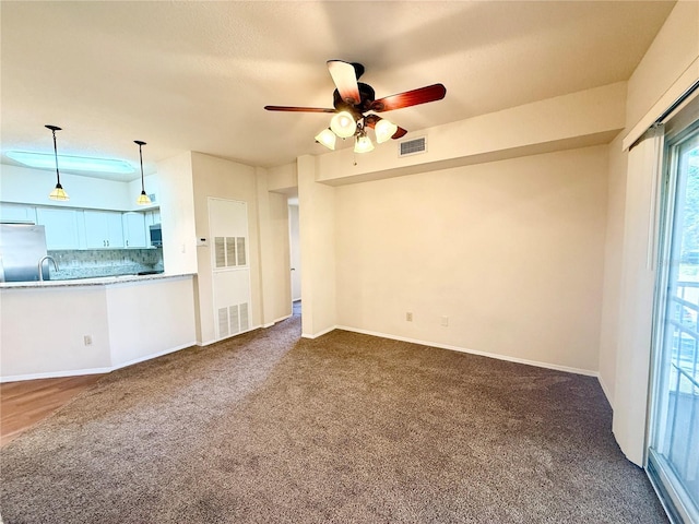 unfurnished living room with sink, ceiling fan, and dark colored carpet