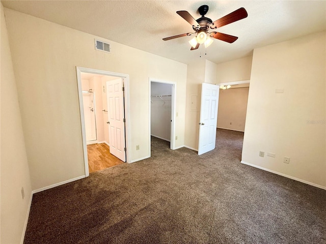 unfurnished bedroom with a walk in closet, carpet flooring, a textured ceiling, and a closet