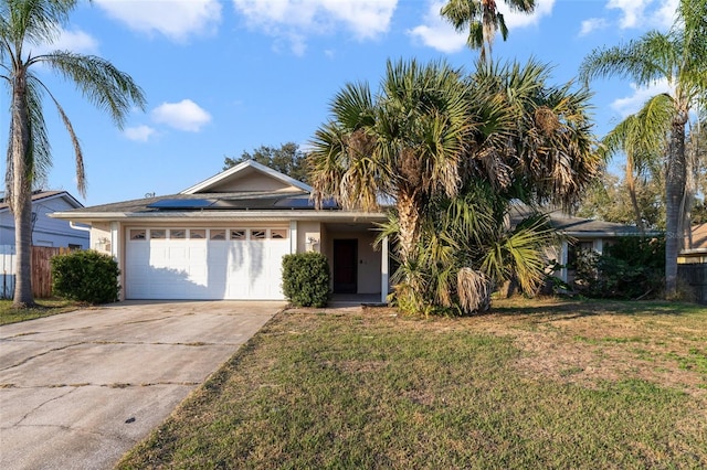 ranch-style house with a garage, a front lawn, and solar panels