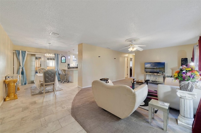 living room with ceiling fan with notable chandelier and a textured ceiling