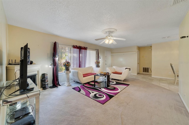 carpeted living room featuring ceiling fan and a textured ceiling