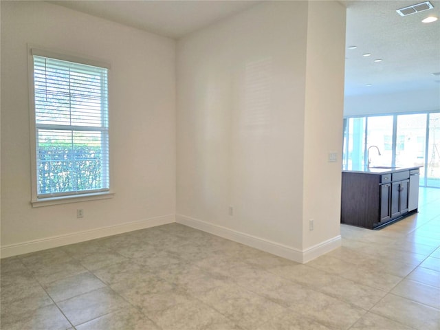 spare room featuring recessed lighting, a sink, visible vents, and baseboards