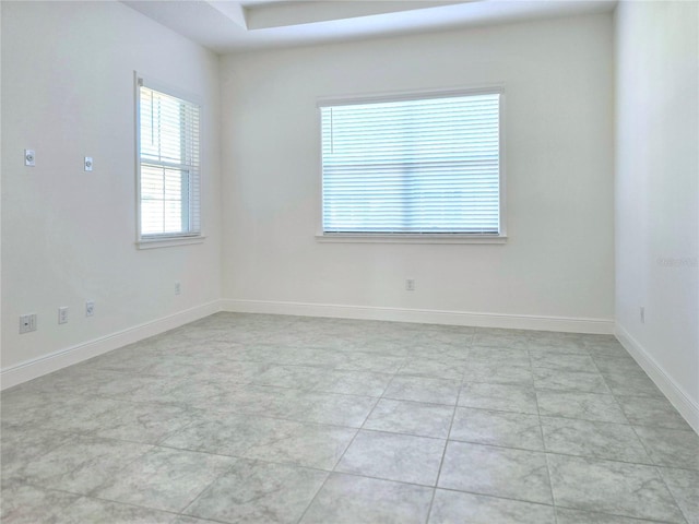 spare room featuring light tile patterned flooring and baseboards