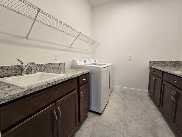 clothes washing area featuring cabinet space, light tile patterned flooring, a sink, separate washer and dryer, and baseboards