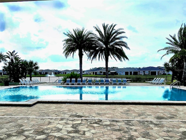 community pool with a residential view, fence, and a patio