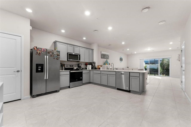 kitchen featuring gray cabinetry, sink, kitchen peninsula, and appliances with stainless steel finishes