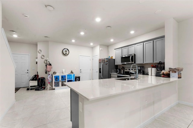 kitchen with light stone counters, appliances with stainless steel finishes, gray cabinets, and kitchen peninsula