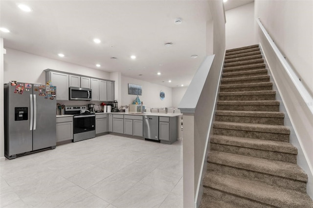 kitchen with appliances with stainless steel finishes, gray cabinets, and kitchen peninsula