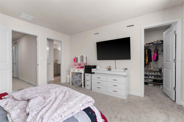 bedroom with a walk in closet, light colored carpet, and a closet