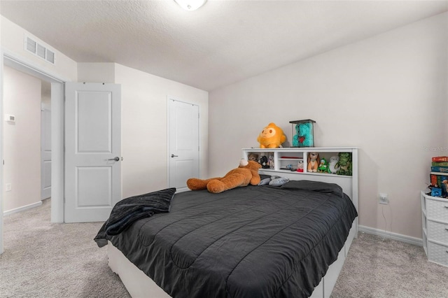 bedroom with light colored carpet and a textured ceiling