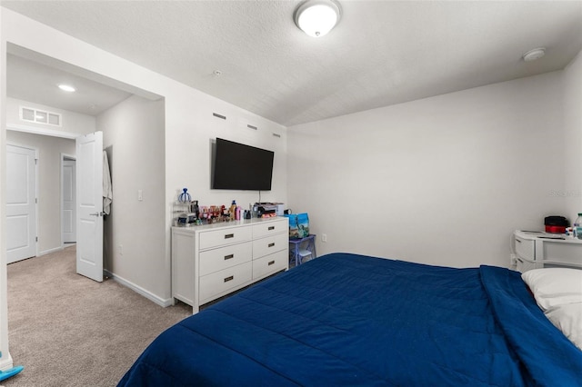 bedroom featuring light colored carpet and a textured ceiling