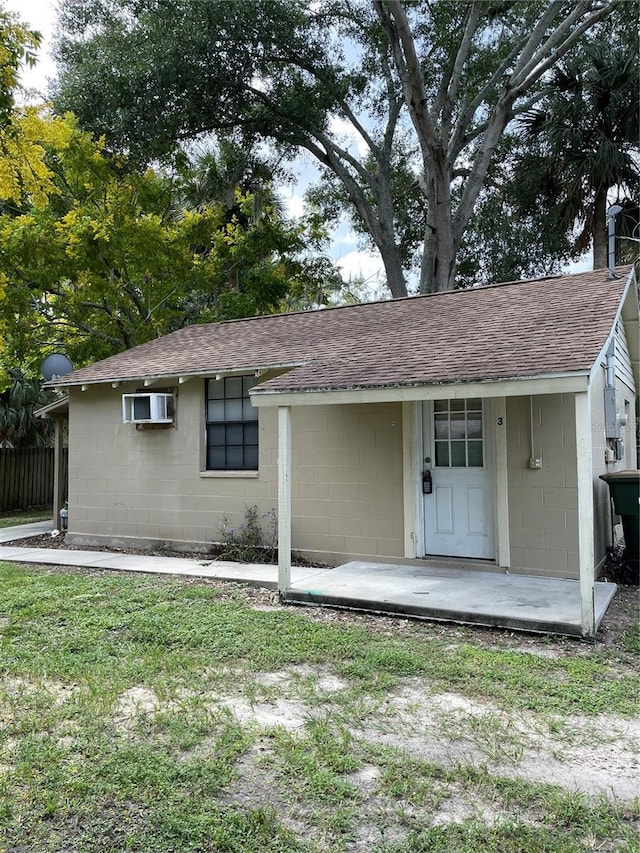 view of front of property with a wall mounted AC and a front lawn